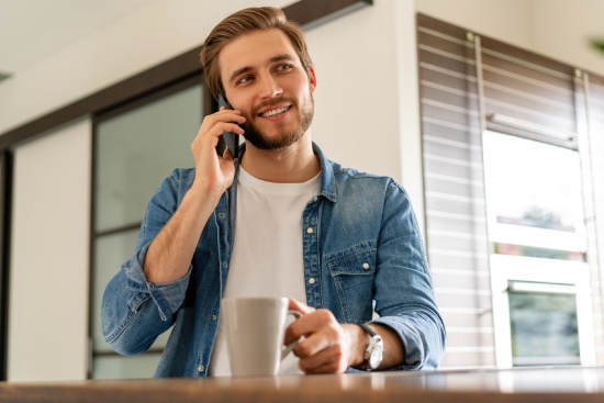 Smiling man at home using cell phone.