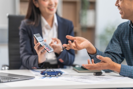 Asian businesswoman specializing in car loan services. Proficient in terms like extended warranty, lease, MSRP, and navigating financing options for customers' automotive needs.